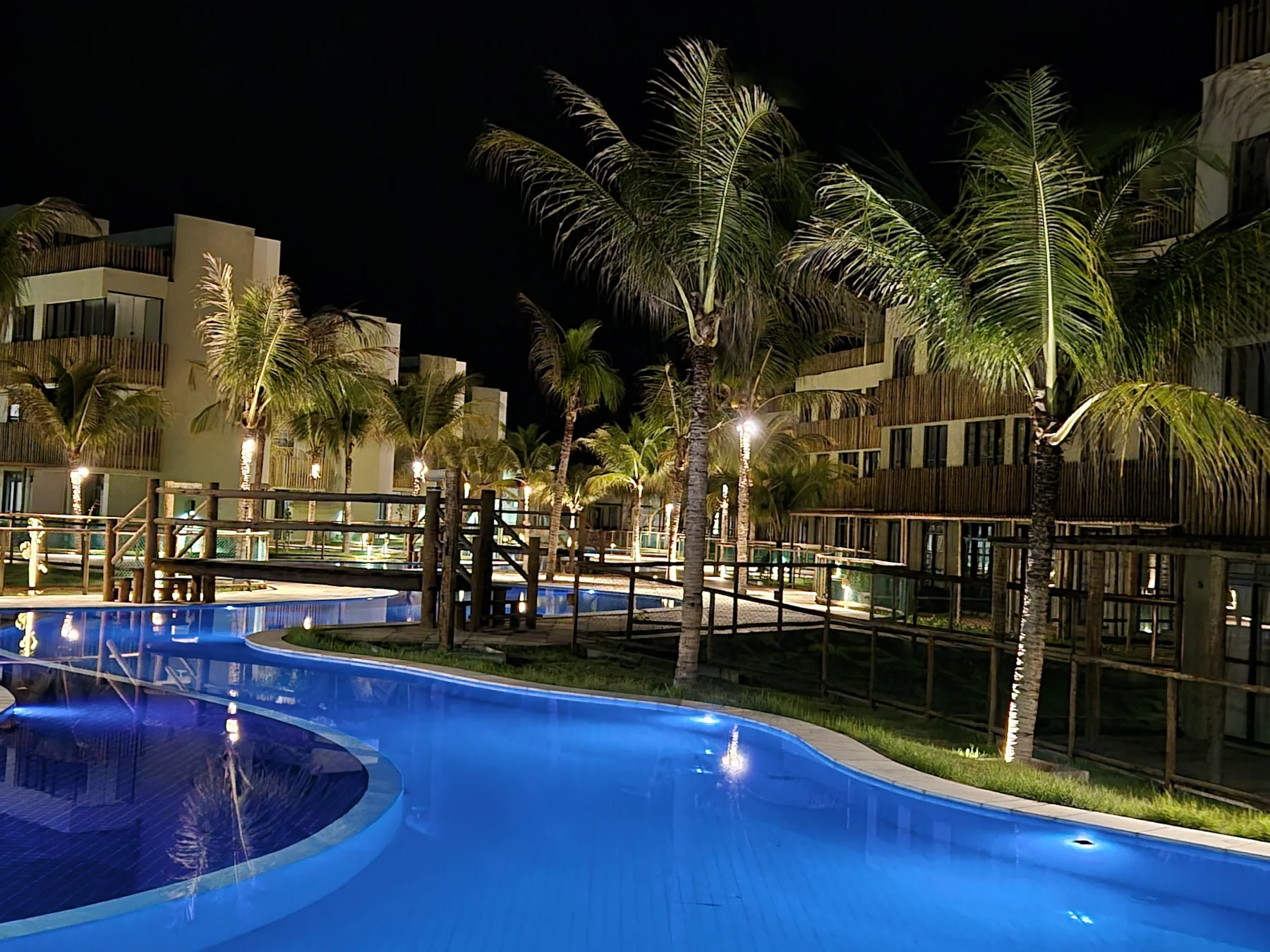 Piscina iluminada entre os coqueiros